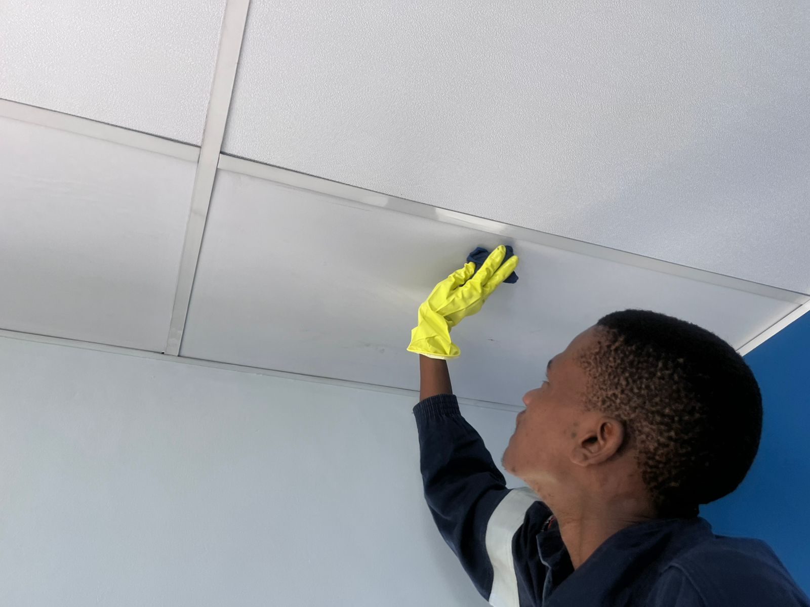 Worker reaching up to clean ceiling panel